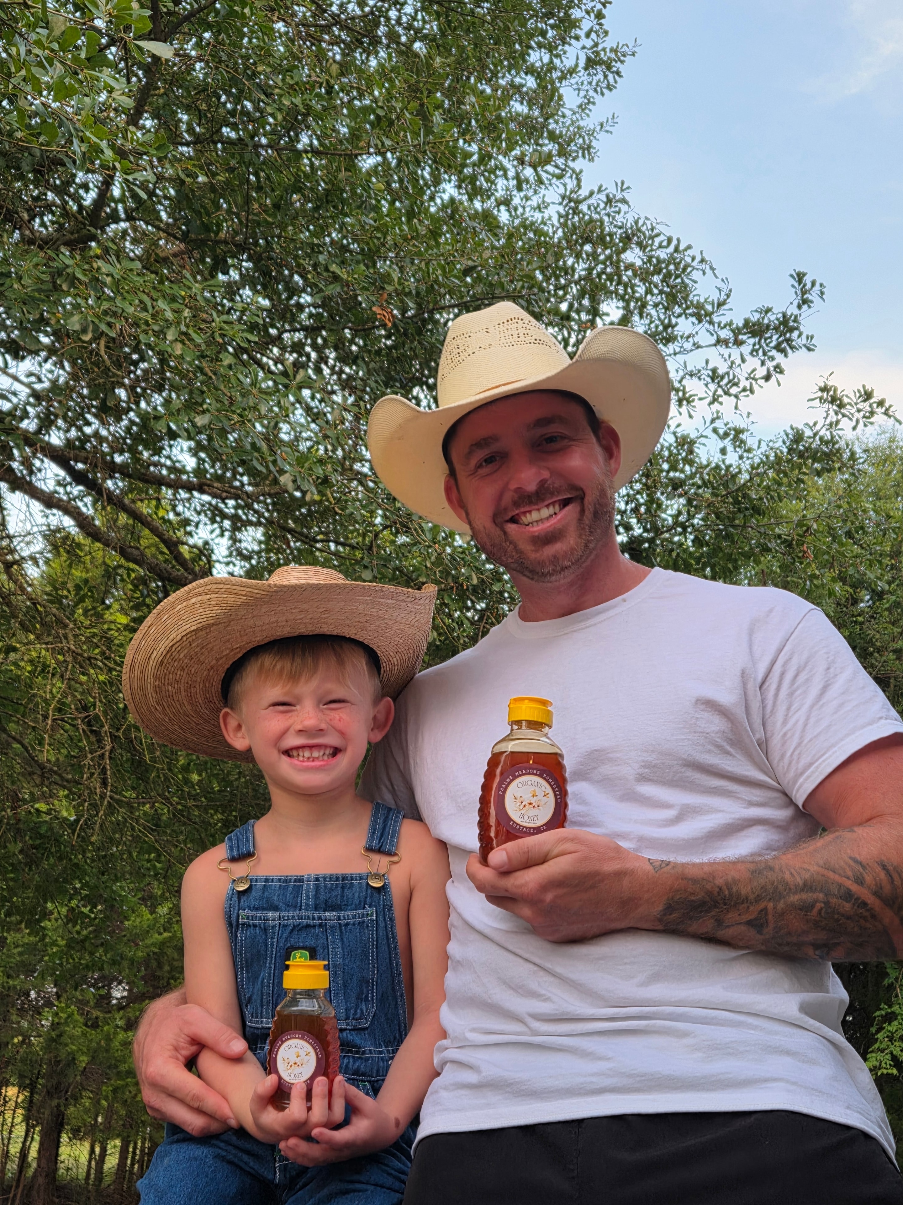 Dad and son in cowboy hats holding honey